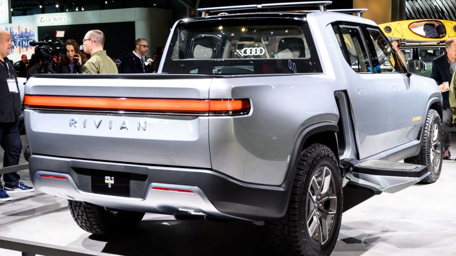 A silver Rivian R1T sitting on a white pad indoors.