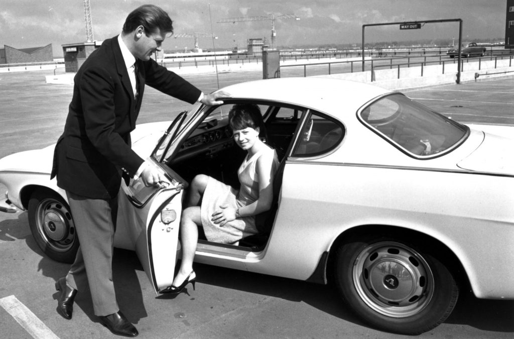 Roger Moore opening the Volvo P1800's door for 'The Saint' co-star Isabelle McMillan