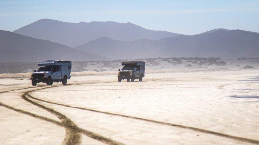 Two camper trucks driving through the desert