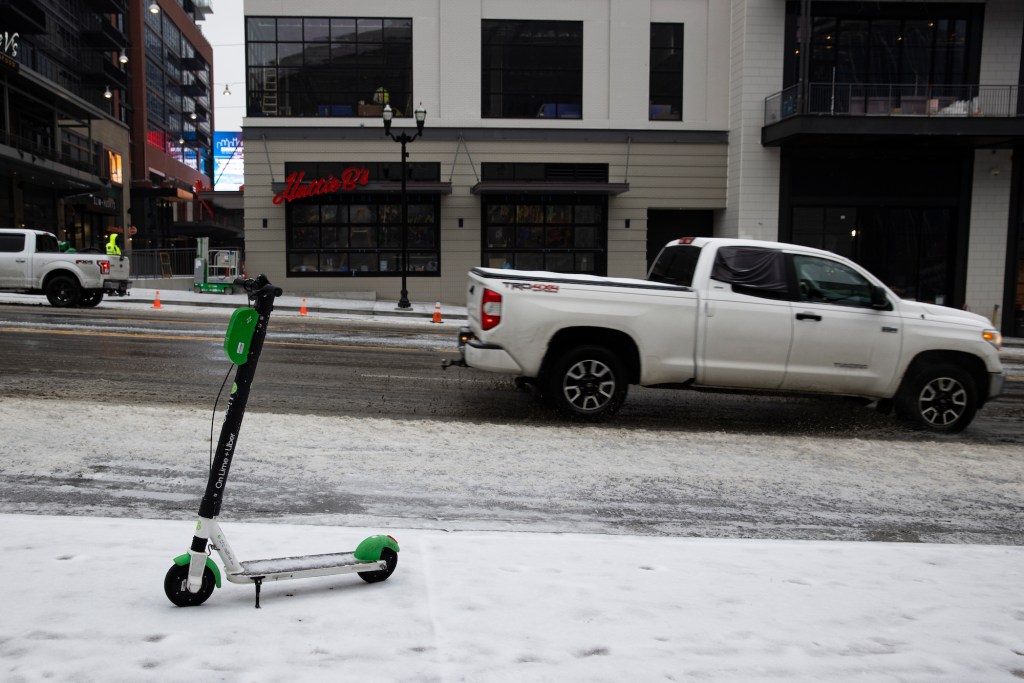 An electric scooter popular with tourists stands on an ice-covered sidewalk. 