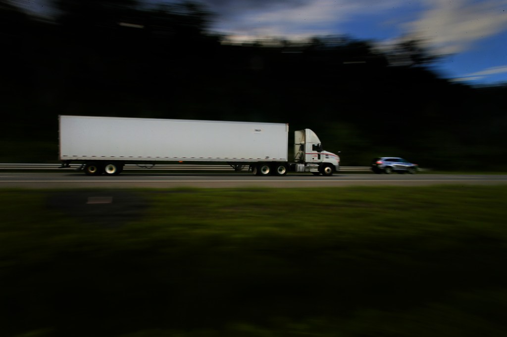 Semi-truck and car driving down highway