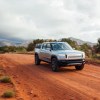 Silver Rivian R1T electric truck driving on a dirt road