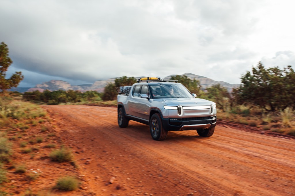 Silver Rivian R1T electric truck driving on a dirt road
