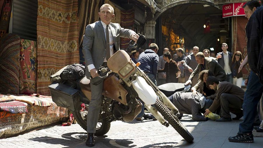 This is a still of Daniel Craig on a Honda CRF250R during Skyfall. Daniel Craig’s Stunt Double reveals the Secrets of the Iconic James Bond Motorcycle Chase in Skyfall. Bond will get back on a motorcycle to complete the No Time to Die motorcycle jump | MGM/Eon Productions/James Bond 007 Youtube Channel