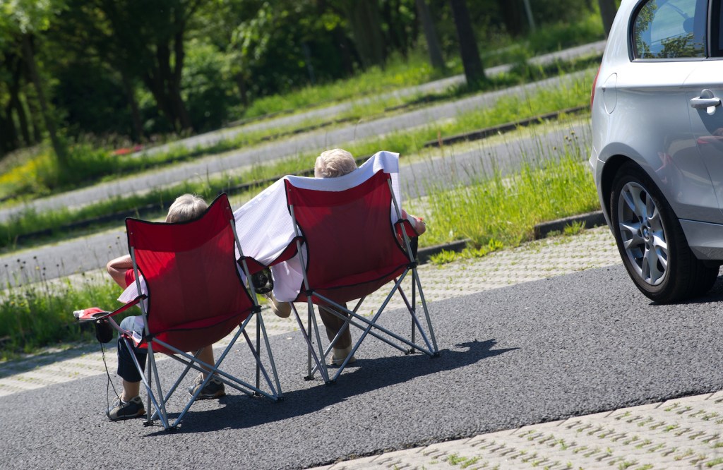 This is a couple setting up their camping chairs in a parking lot. Many businesses and churches allow car dwellers to park overnight legally. | Uwe Zucchi/picture alliance via Getty Images