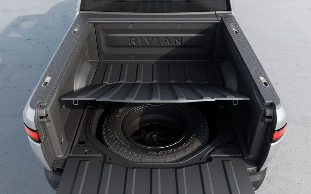 Spare tire under the pickup bed of a silver Rivian R1T