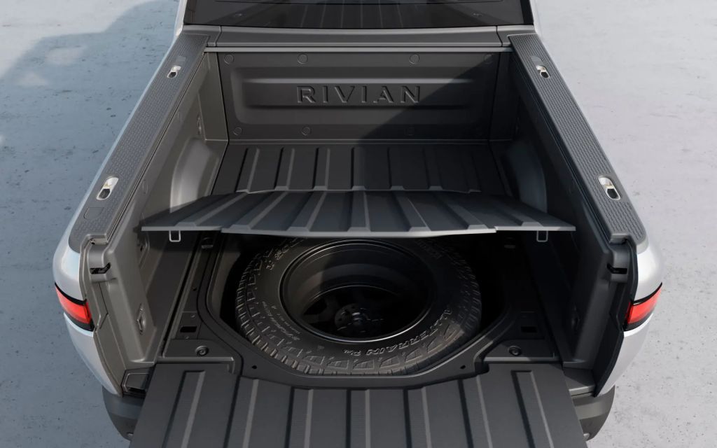 Spare tire under the pickup bed of a silver Rivian R1T