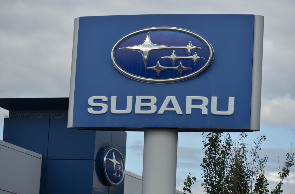 Subaru sign with the logo and name written on it in front of a cloudy background.