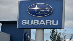 Subaru sign with the logo and name written on it in front of a cloudy background.