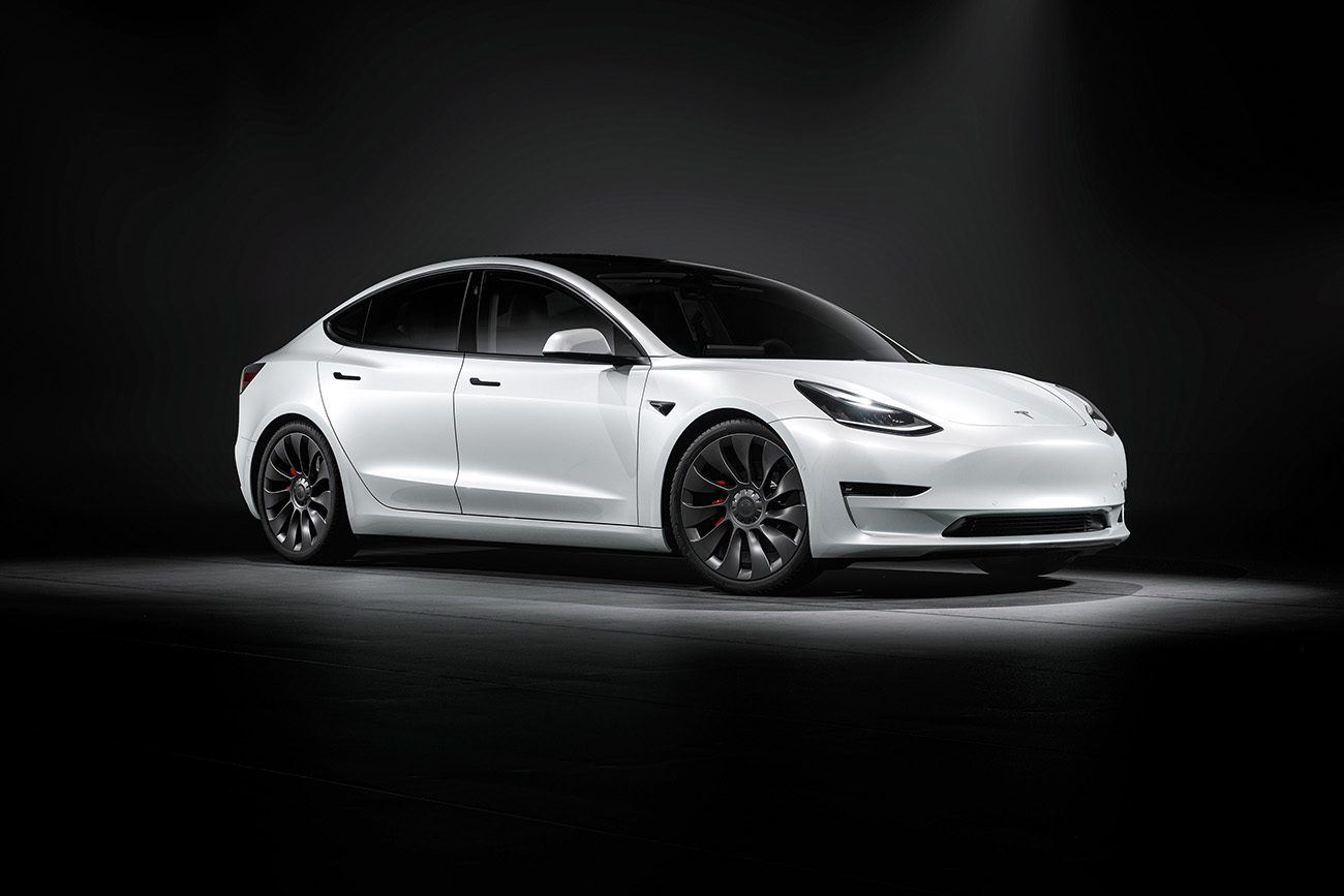 Tesla Model 3 in white photographed in a black studio environment. electric vehicle
