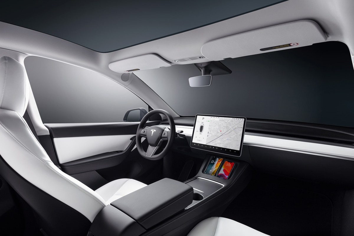 Tesla Model Y interior featuring a black dashboard and center console with white seats and roof liner