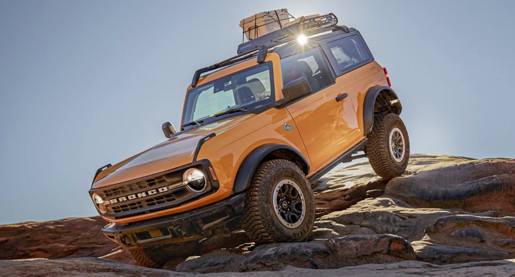 A yellow 2021 Ford Bronco is crawling on rocks. 