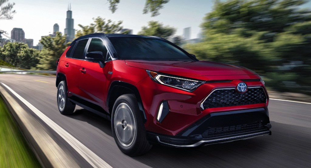 A red 2021 Toyota RAV4 Prime is driving on the road.