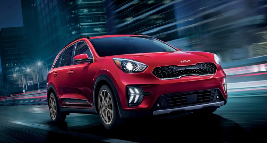 A red 2022 Kia Niro is driving on the road. 