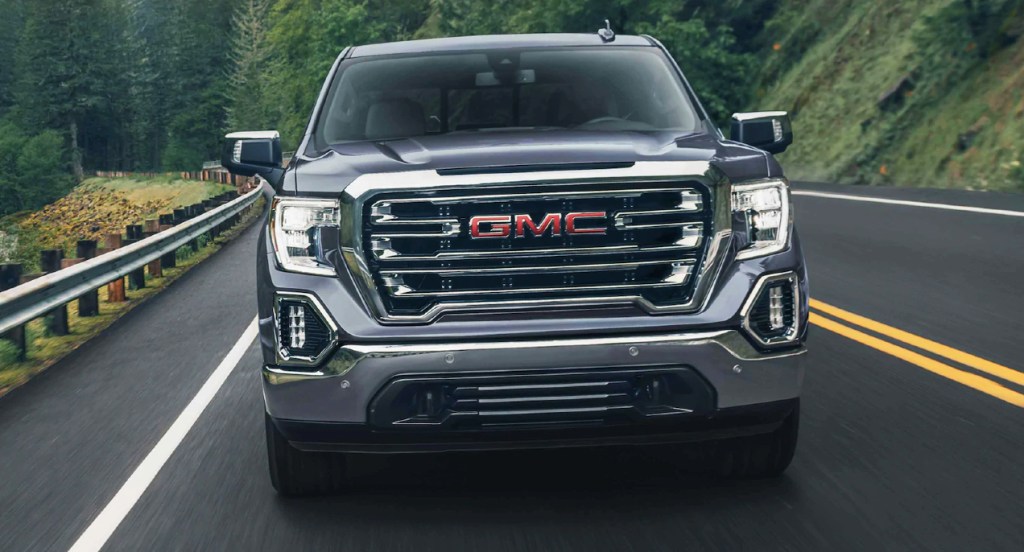 A gray GMC Sierra 1500 is driving down a road.