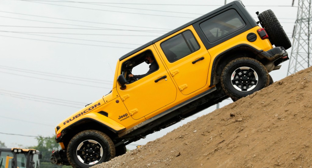 A yellow Jeep Wrangler is going down a hill.