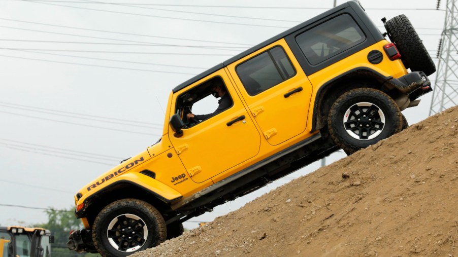 A yellow Jeep Wrangler is going down a hill.