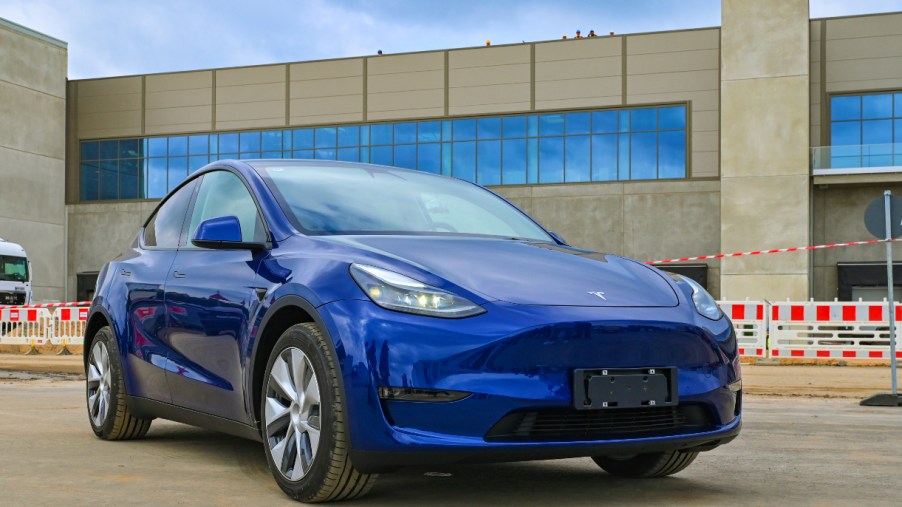 A blue Tesla model Y is parked.