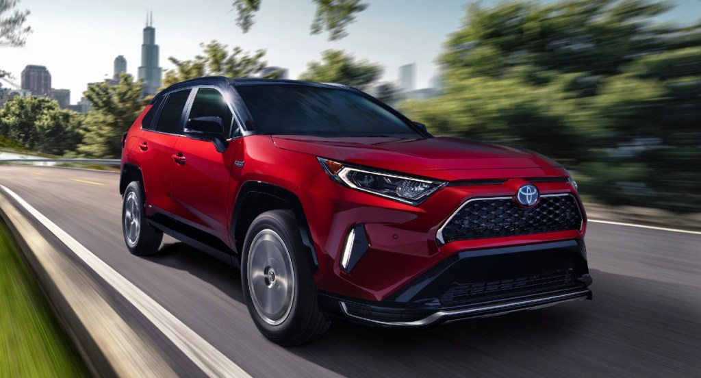 A red Toyota RAV4 Prime is driving on the road. 