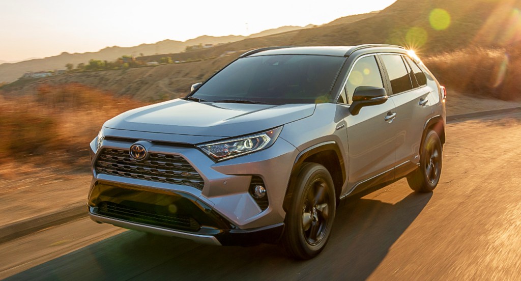 A gray Toyota RAV4 hybrid SUV is driving on the road.