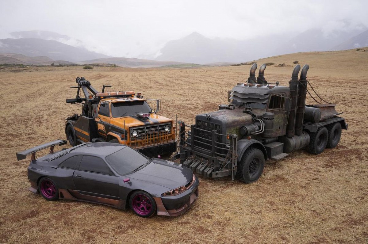Image of the "Terrorcons" from the upcoming film Transformers: Rise of the Beasts featuring a Nissan R33 Skyline GT-R, a GMC 7000 tow truck, and a Peterbilt semi-truck