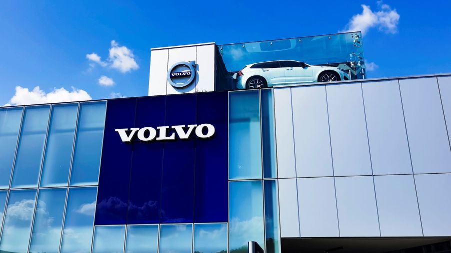 A Volvo building with a car displayed on top and the name written on the sign over many windows.