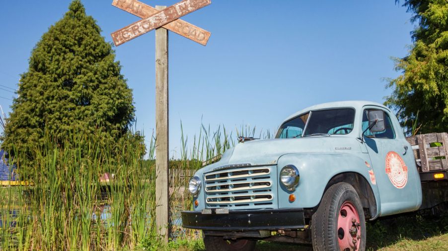 A weathered blue Studebaker 2R Series pickup truck by an overgrown railroad track
