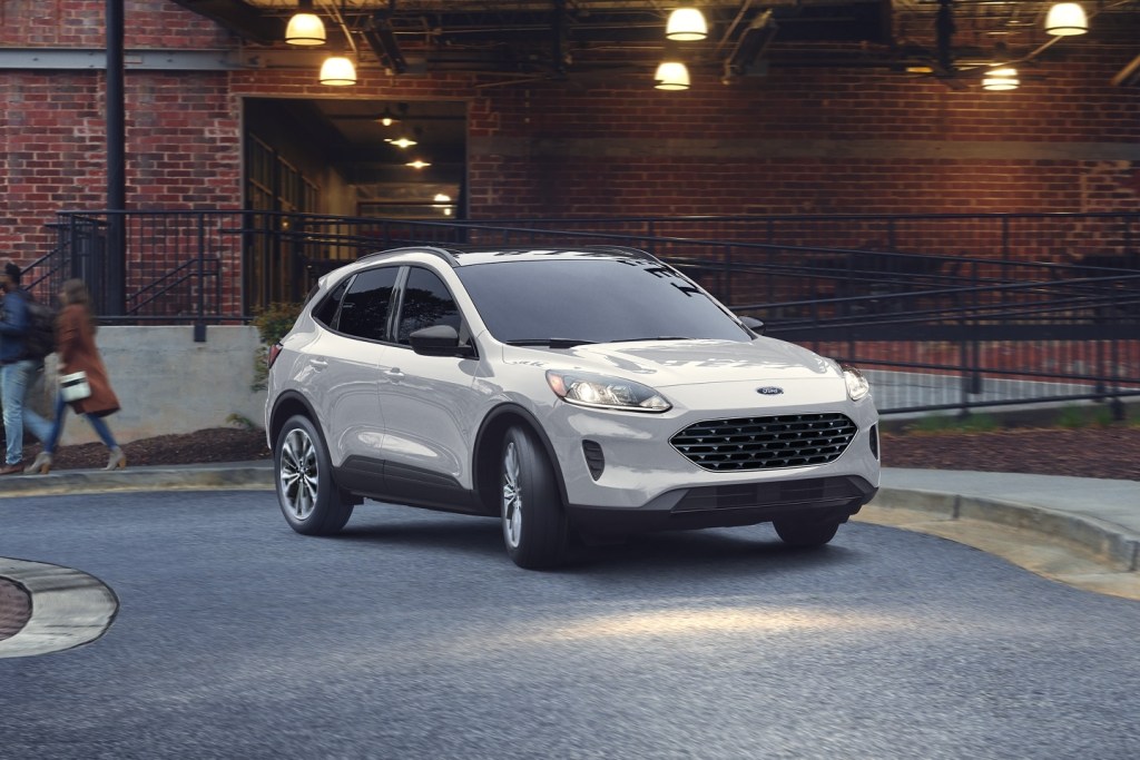 White 2022 Ford Escape PHEV driving by a brick building