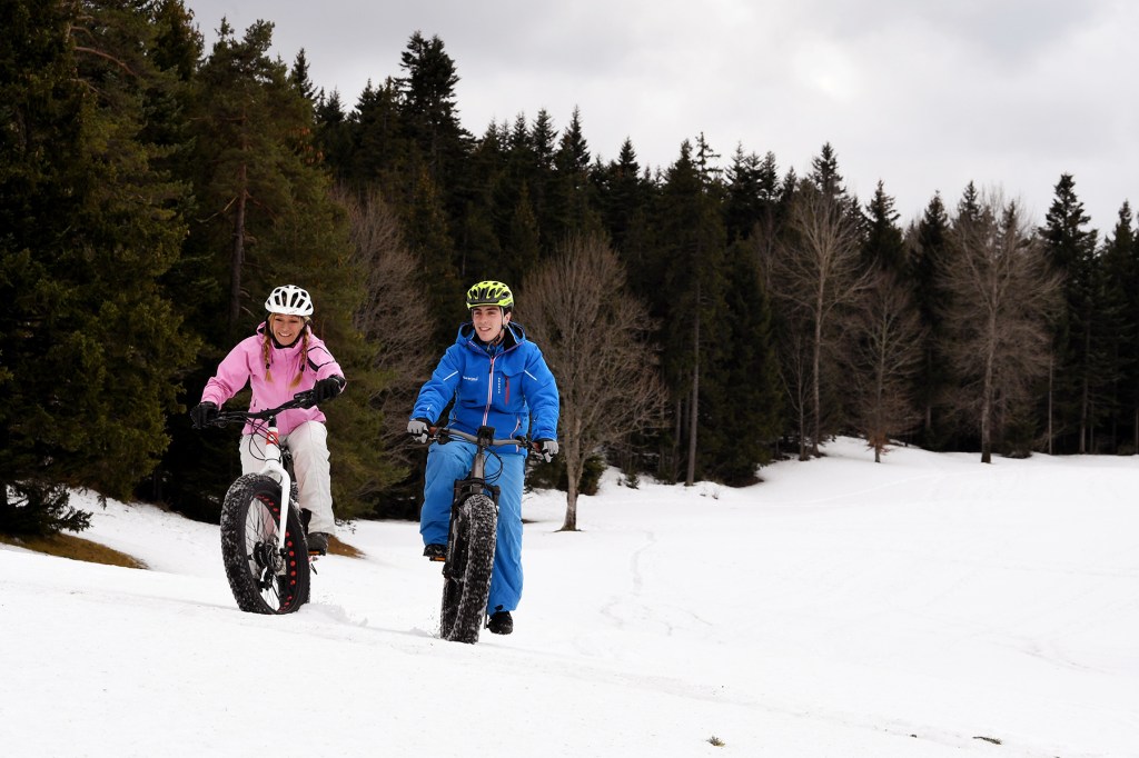 People ride Fat Bike electric bicycles on a snow-covered field.