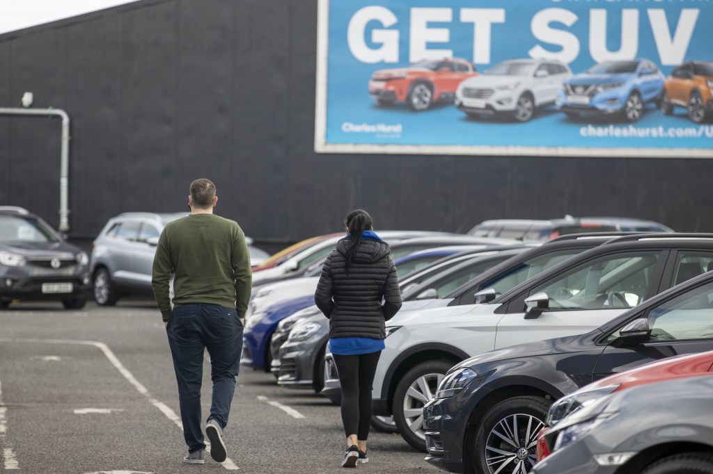 Potential customers walk around a used car dealership