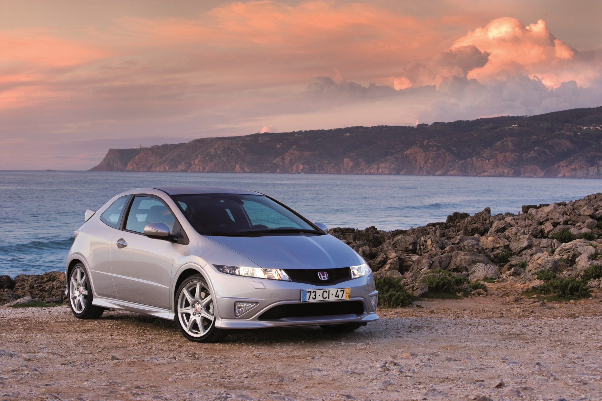 A silver FN2 generation Honda Civic Type R shot at the seaside from the front 3/4