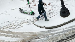 A man walks away from a scooter in that's parked in the snow