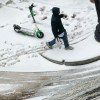 A man walks away from a scooter in that's parked in the snow