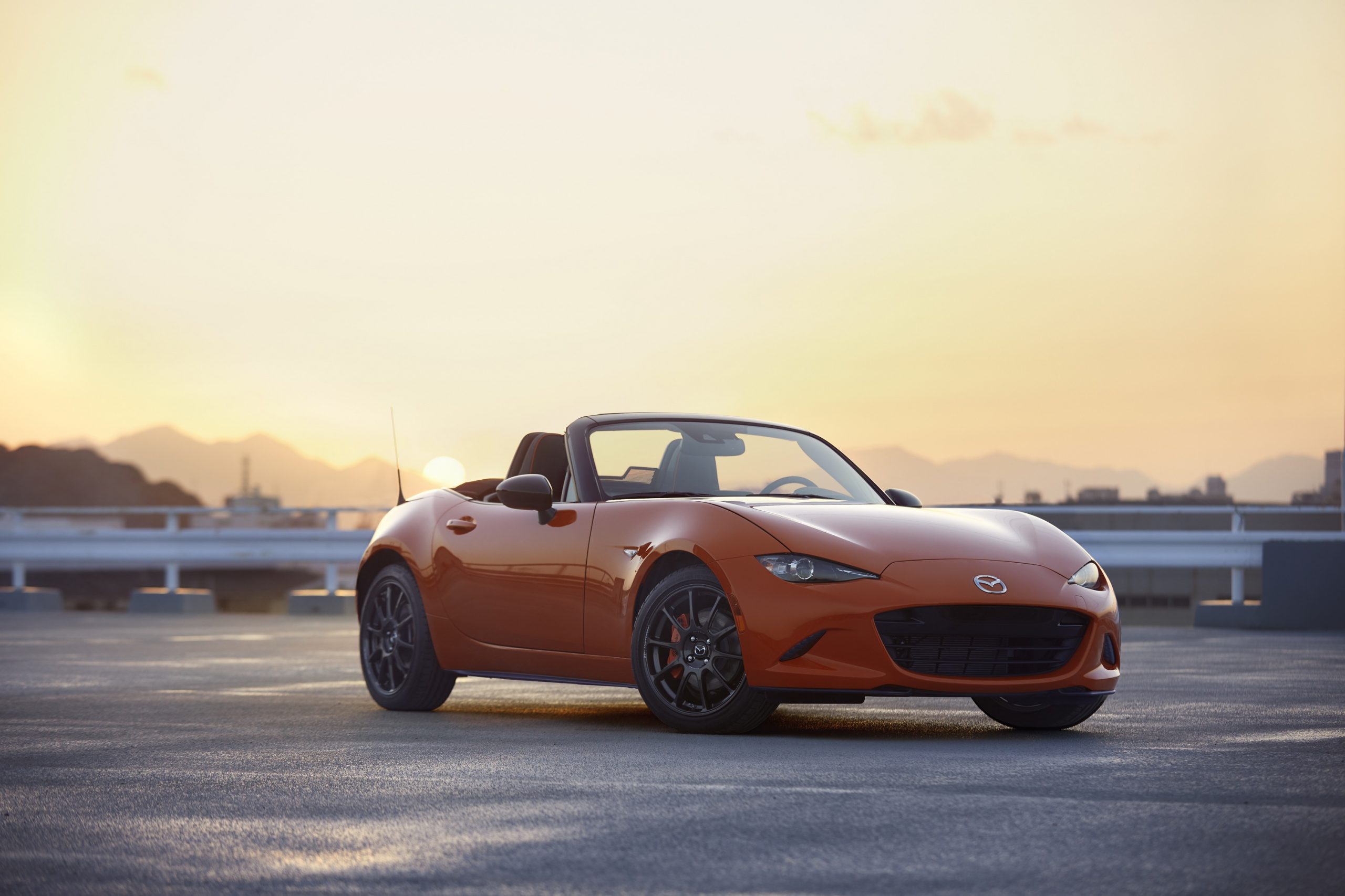 The current generation Miata with open top shot from the front 3/4 at sunset