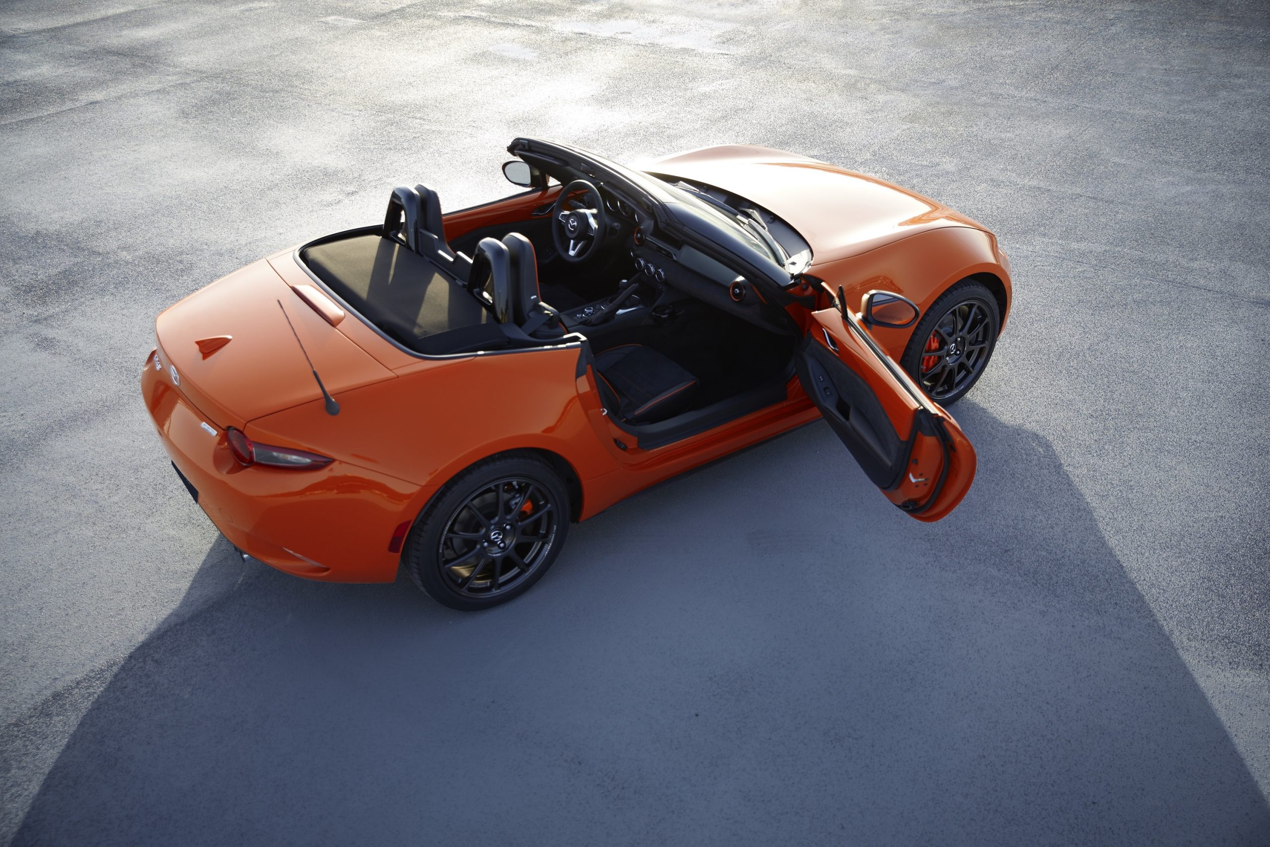 The 2021 Mazda Miata shot from the high 3/4 in orange with doors open