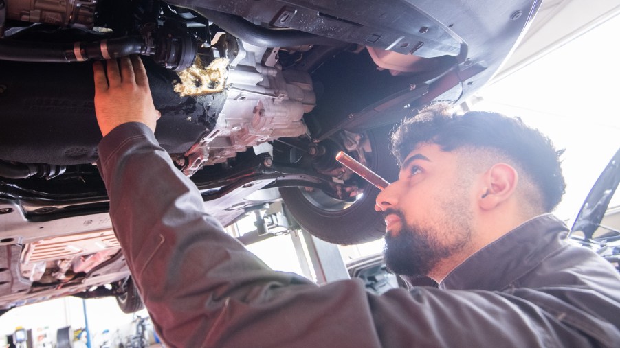 A mechanic checks underneath a car