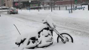 A motorcycle covered in snow after a crazy winter storm.