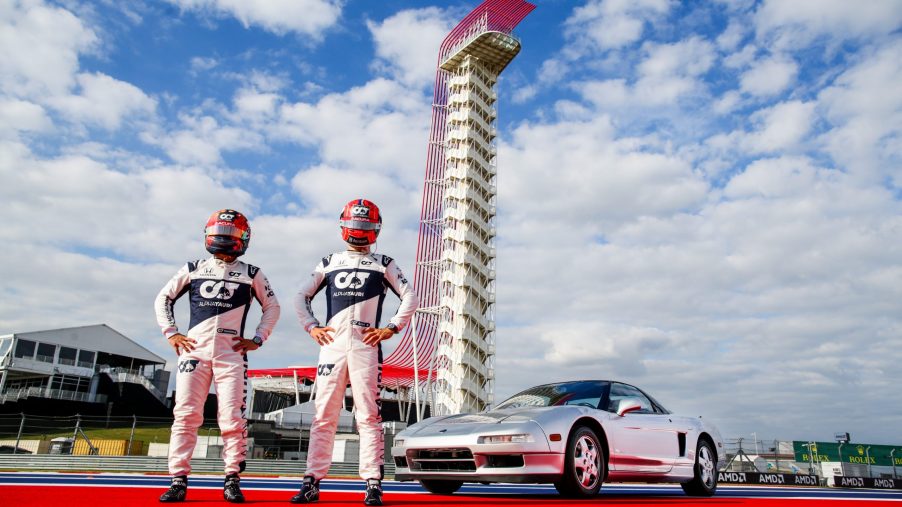 Pierre Gasly and Yuki Tsunoda stand in front of a silver Acura NSX at the Circuit of the Americas