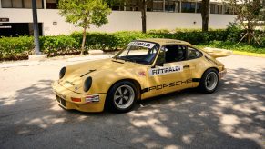 A yellow Porsche 911 RSR race car, shot from the far 3/4 angle in the shade