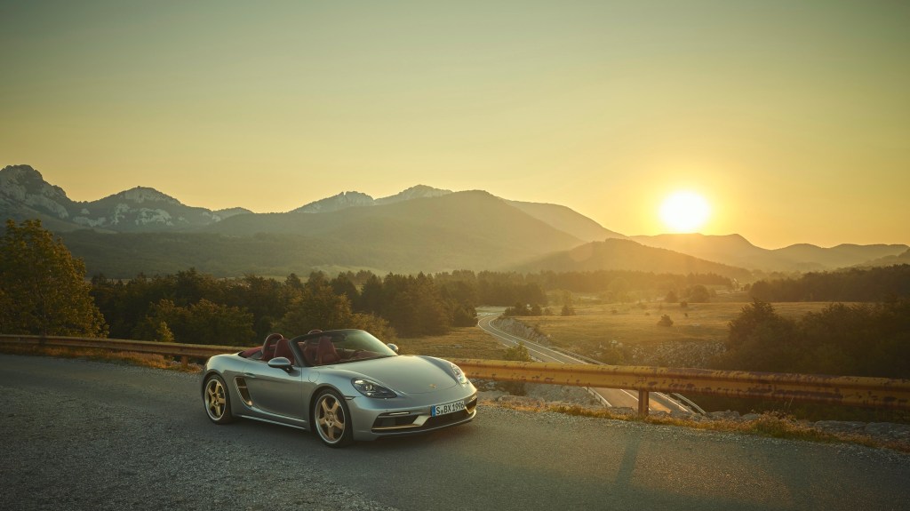 The silver 2022 Porsche Boxster Anniversary shot at sunset on a canyon road from the front 3/4