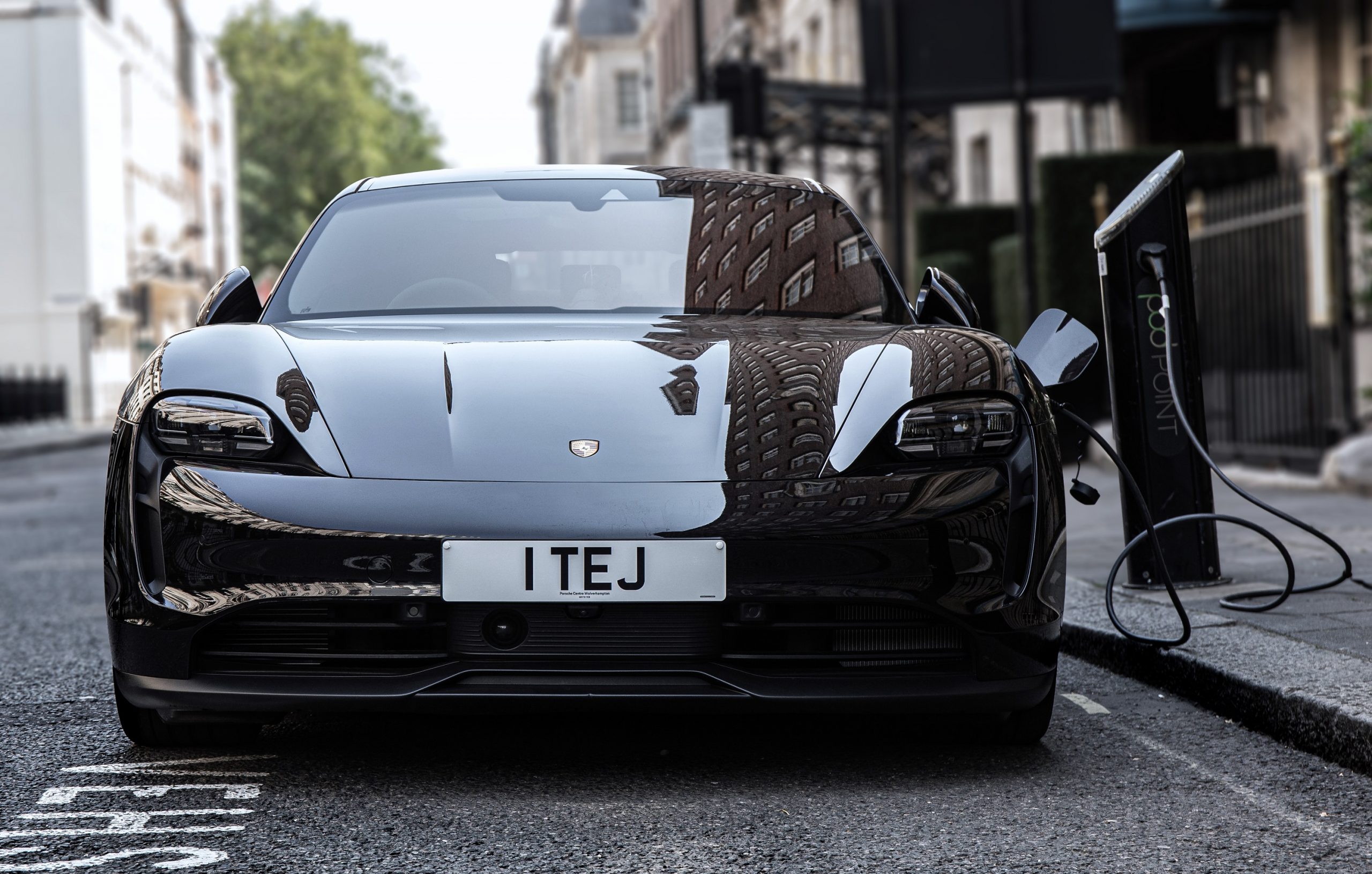 A black Porsche Taycan charging on the street in London, shot from the front