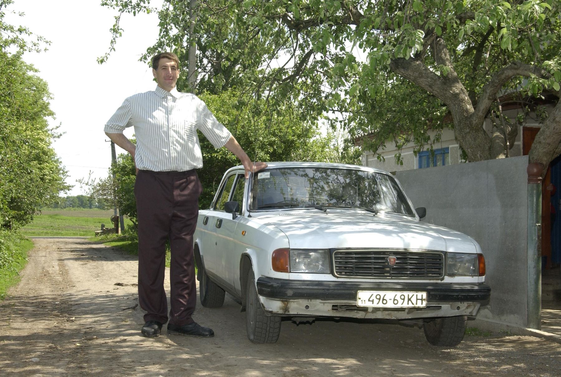 The reported tallest man in the world from Ukraine standing next to a Russian Volga car model