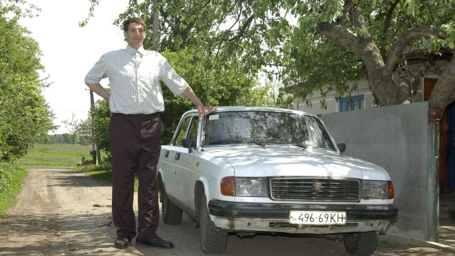 The reported tallest man in the world from Ukraine standing next to a Russian Volga car model