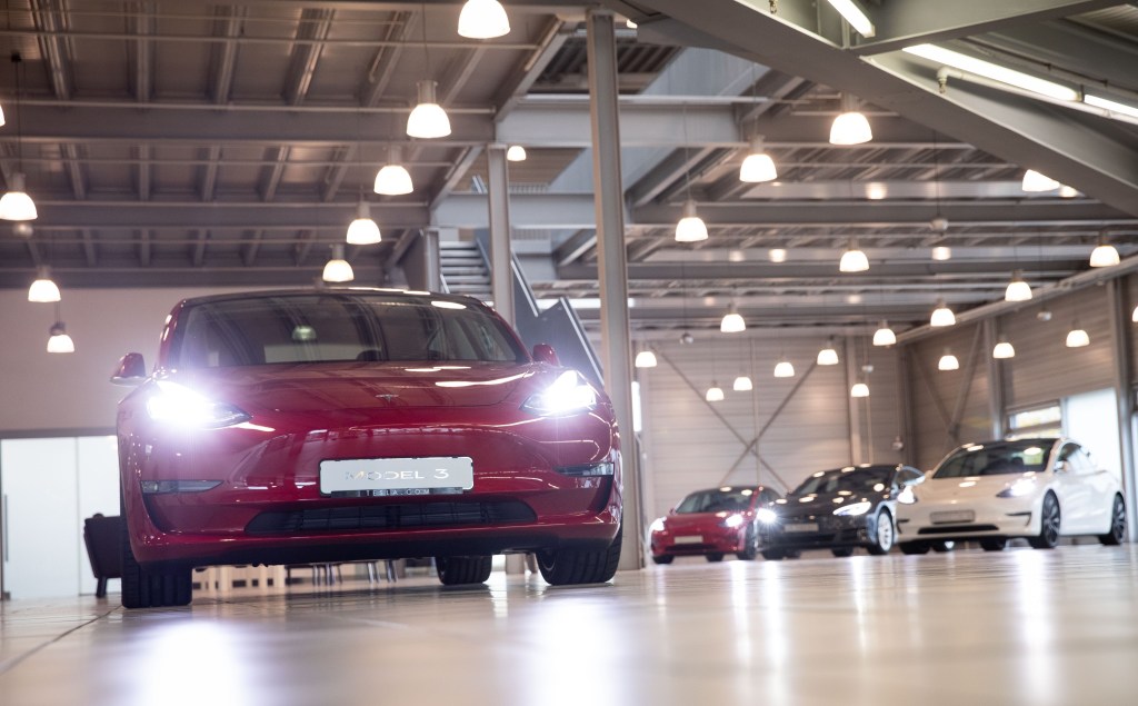 A red Tesla Model 3 electric car in a service center shot from the front