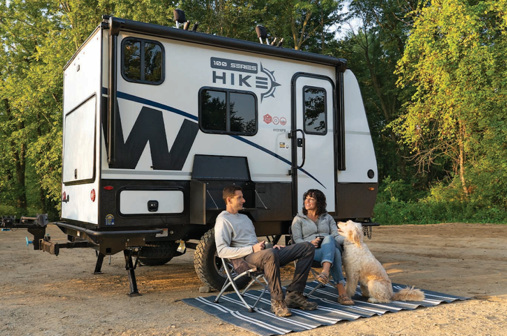 a couple sitting outside the Hike 100 small camper