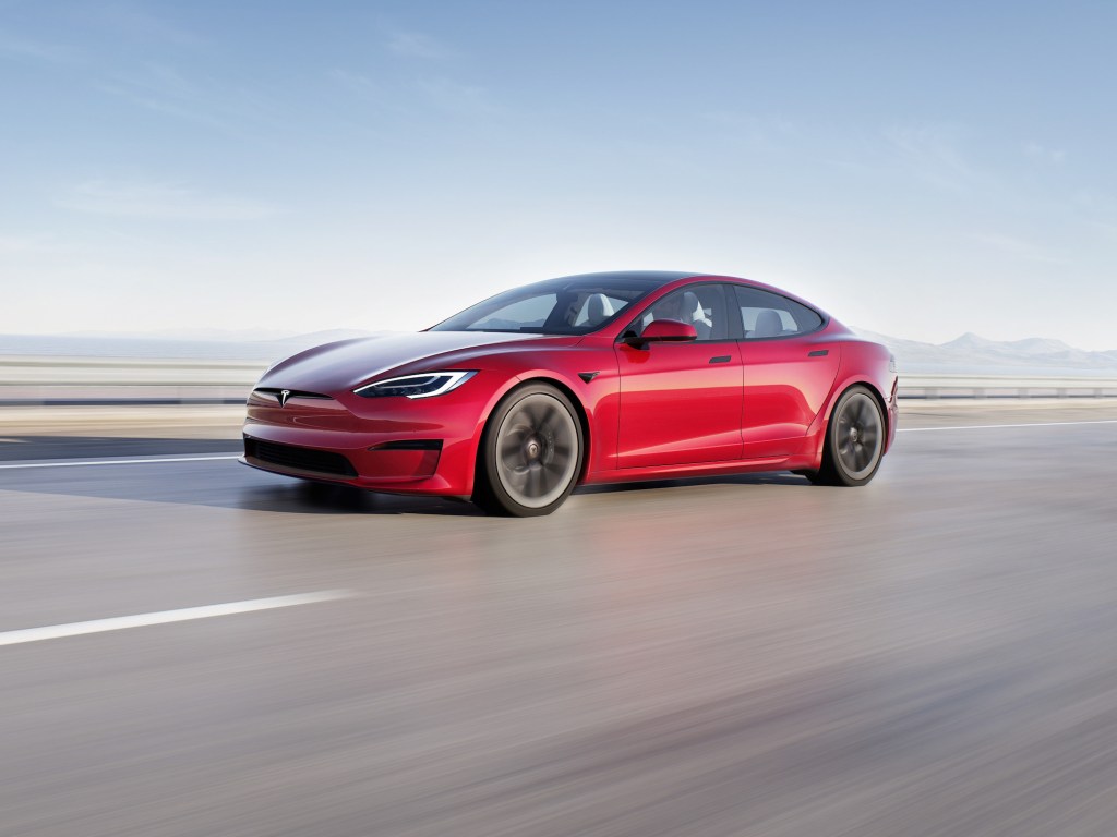 a 2021 Tesla Model S Plaid in red speeding down a road