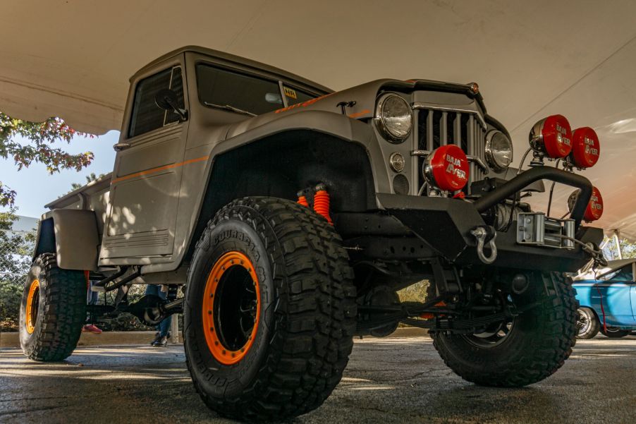A low-angle front 3/4 view of a gray 1955 Willys-Overland Jeep Truck at the 2021 Mecum Chicago auction