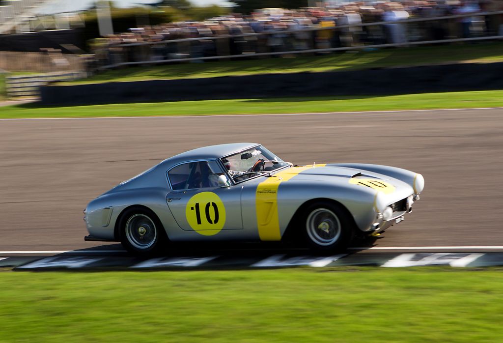 A silver-and-yellow 1960 Ferrari 250 GT SWB Competizione racing on the track at the 2018 Goodwood Revival