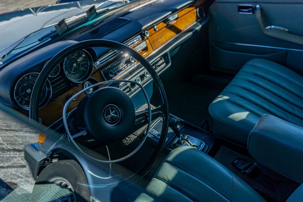 The blue-leather-upholstered front seats and wooden dashboard of a 1972 Mercedes-Benz 280SE 3.5 at the 2021 Chicago Mecum auction