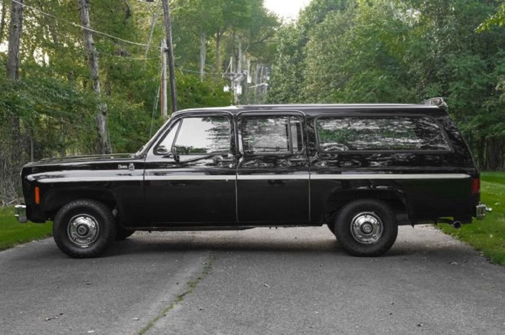 A black 1976 GMC Suburban Sierra parked outside.